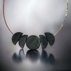 Full Moon Necklace - Black wood beads on Gold Chain This statement necklace is a versatile addition to anyone's collection. In our black full moon phase necklace - affectionately named the Kristy Necklace - one full black wood circle is flanked by 4 black half moon circles. Perfect for adding a hint of intrigue to any outfit, the Full Moon Necklace effortlessly transitions from day to night with ease. Whether you're heading out for brunch or a night on the town, this necklace is the ultimate jew Handmade Circular Black Necklaces, Handmade Black Circle Necklaces, Handmade Black Circle Necklace, Handmade Circular Black Necklace, Black Moon Phase Round Pendant Necklace, Black Necklace With Moon Charm, Handmade Black Moon Necklace, Black Round Necklace With Moon Charm, Minimalist Black Moon Necklace