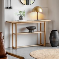 a living room with a table, mirror and vase on the wall next to it