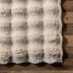 a white and brown checkered blanket laying on top of a wooden floor