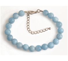 Embrace the serene beauty of the ocean with this sterling silver bracelet, adorned with round beads of blue milky aquamarine. Its subtle rhodium plating enhances the bracelet's allure, while the secure lobster claw clasp ensures it stays with you through all your adventures. Aquamarine Bracelet Beads, Aquamarine Beads, Sterling Silver Bracelet, Blue Beads, Jewelry Bags, Bead Bracelet, Lobster Claw, Sterling Silver Bracelets, Round Beads