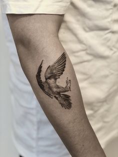 a black and white photo of a bird tattoo on the left upper half of the arm