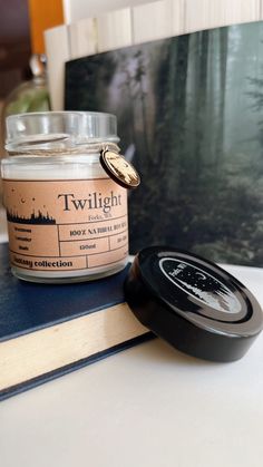 a candle sitting on top of a book next to a jar of candles and an open book