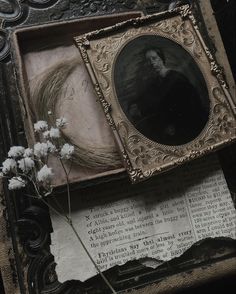 an old photo frame with flowers on top of it next to a book and paper