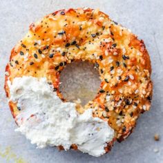 a doughnut covered in cheese and sprinkled with black sesame seeds, sits on a piece of parchment paper