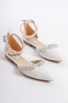 two white shoes with jeweled straps on them