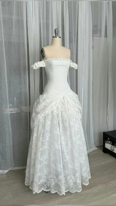 a white wedding dress on display in front of curtains