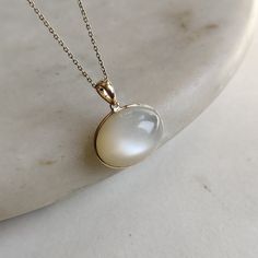 ITEM DESCRIPTION: >>The pendant is made from Solid 14K Yellow Gold. Gemstone used is absolutely natural and ethically sourced.  >>Natural White Moonstones cabochon with bezel setting are studded on it with utmost precision.  >>This is a minimalist design and is absolutely hassle-free and everyday jewelry.  ✓ Gem: White Moonstone ✓ Gem size: 14x19 mm oval ✓ Gem weight: 17.18 carats ✓ Gold purity: 14K (58.33% approx.) ✓ Gold weight: 0.58 grams  ✓ Gross weight: 4.02 grams The Gold purity is guaranteed and it comes with authentic 14K gold hallmark. Since these Pendants are handmade, they are Nickel/Lead FREE.  CUSTOMIZATION: --> You can choose your own gemstone as well. --> Main Gemstone can be substituted with the gem of your choice. --> Kindly drop a message for the same. CUSTOMER SUPPORT: - Moonstone Jewelry Set, Elegant Moonstone Ring As Gift, Elegant Moonstone Round Stone Jewelry, Luxury Si Clarity Moonstone Jewelry, White Moonstone 14k Gold Ring Gift, White Gold Polished Moonstone Jewelry, White Gold Moonstone Jewelry With Polished Finish, Elegant Moonstone Ring With Natural Stones For Anniversary, Elegant Moonstone Jewelry