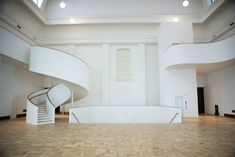 an empty white room with stairs and windows