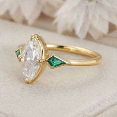 a close up of a ring with a diamond and green stones on it's side