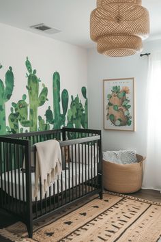 a baby's crib in front of a cactus mural