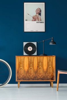 a record player sitting on top of a wooden cabinet in front of a blue wall