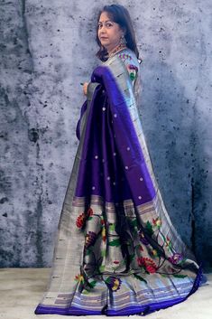 This exquisite regal paithani saree is handwoven in bluish purple color. Silver zari dollar buttis adorn the body while the silver zari border is decorated with handwoven in muniya border. The elaborate pallu is woven with colorful lotus along with winding vines. The saree comes with plain blouse with matching borders. Approximate Length 6.5 mtrs (inclusive of blouse length)Height - 48- 52" Saree comes with fall, picot and tassels done. Blouse piece is cut. Approximate weight - 1.8 lbs Kindly Note : The colors you see on your device may vary due to the color reproduction, brightness and resolution of individual devices. If you'd like more clarity before your purchase, please contact our support team. Purple Paithani Saree, Paithani Silk Saree, Bluish Purple, Paithani Saree, Silk Saree Blouse Designs, Silk Saree Blouse, Saree Trends, Plain Blouse, Support Team