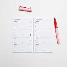 an open notebook with a red pen next to it on top of a white surface