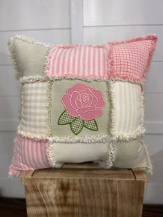 a decorative pillow with a pink rose on the front and white stripes on the back