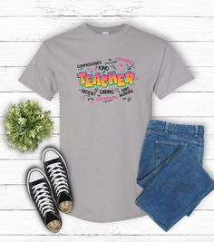 A fun and vibrant T-shirt that says 'Teacher' in graffiti style, surrounded by positive description words. Perfect for educators who want to showcase their passion for teaching in a unique and bold way. This shirt is ideal for Teacher Appreciation Week, back-to-school season, or as a thoughtful gift for a teacher. Product features - Knitted in one piece without side seams - Highly elastic ribbed knit collar - Made from specially spun fibers for durability - Classic fit for year-round comfort - P Multicolor Relaxed Fit T-shirt With Graffiti Print, Funny Multicolor Short Sleeve T-shirt, Funny Multicolor Pre-shrunk T-shirt, Fun Multicolor T-shirt With Letter Print, Multicolor Graphic Tee With Text Print, Multicolor Graffiti Print T-shirt With Relaxed Fit, Multicolor Graffiti Print Relaxed Fit T-shirt, Fun Multicolor T-shirt With Text Print, Fun Short Sleeve Tops With Graffiti Print