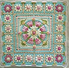 a crocheted square with pink and white flowers in the center on a blue background