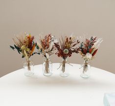 three vases filled with dried flowers on top of a table