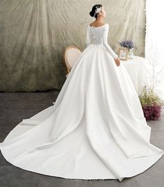 a woman in a white wedding dress sitting on a chair with her back to the camera