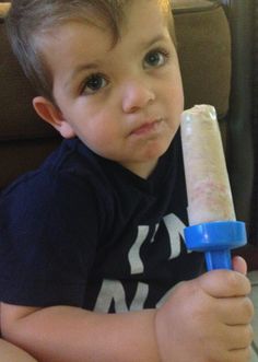 a little boy sitting on the floor holding a large ice cream cone in his hand