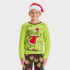 Surprise your kid during Christmas with The Grinch 2-Piece Cozy Pajama Set and Santa Hat. This two-piece pajama set includes a green sleep shirt, a pair of black pajama pants and a Santa hat for a festive look. The top showcases a print of the Grinch wearing a Santa outfit on skis with "Merry Grinchmas" text, while the bottom showcases allover Grinch faces wearing Santa hats and the name "Grinch" for holiday fun. Grinch Faces, Black Pajama Pants, Grinch Pajamas, The Grinch Christmas, Grinch Face, Black Pajamas, Merry Grinchmas, Santa Outfit, Cozy Pajamas