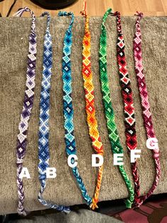 four different colors of braided bracelets sitting on top of a piece of cloth