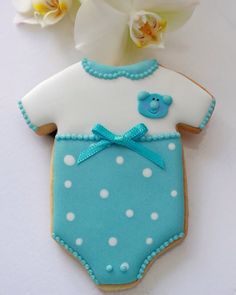 a cookie shaped like a baby's bodysuit with a blue teddy bear on it