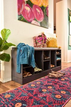 a room with a rug, coat rack and shoes on the floor in front of a painting