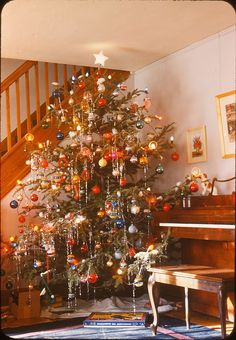 a christmas tree with ornaments on it in front of a piano