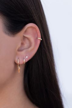 a close up of a person's ear with two small gold earrings on it