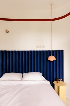 a bed with white sheets and blue headboard