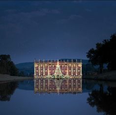 a large building sitting on top of a lake under a sky filled with lots of stars