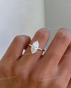 a woman's hand with a diamond ring on her left hand, showing the center stone