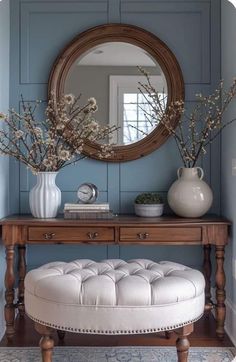 a white bench sitting under a mirror next to a vase with flowers on top of it