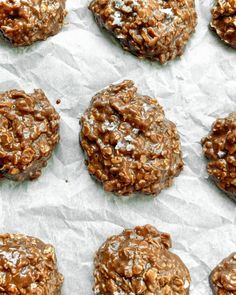 chocolate cookies are arranged on top of white wax paper and lined with brown flecks