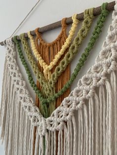 the wall hanging is decorated with multicolored ropes and tassels, along with a wooden stick