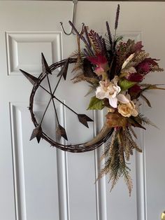 a wreath with flowers and arrows hanging on a door