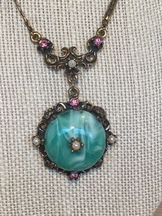 "Gorgeous vintage Victorian / Art Nouveau style necklace / choker features a lovely chain in brass - this is a specialty chain, very intricate and delicate. The pendant portion of the necklace starts at the bottom of the chain with a scroll style collar adorned with flowers of pink rhinestones and tiny faux seed pearls. Dangling beneath is a 1 1/4\" in diameter green and white marbled glass cabochon surrounded with brass filigree, pink rhinestones and pearls and another pearl on top of the glass Vintage Antique Finish Necklace As Gift, Vintage Necklace With Antique Finish As Gift, Vintage Antique Finish Necklace For Gift, Jeweled Metal Necklaces As A Gift, Victorian Cabochon Pendant Necklace, Victorian Pendant Necklace With Cabochon, Victorian Jeweled Pendant Necklace, Antique Gold Cabochon Brass Necklace, Vintage Round Jewelry With Antique Finish