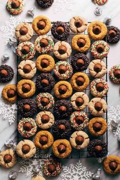 cookies and pastries are arranged on a cooling rack with snowflakes in the background