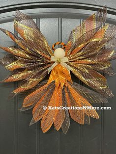 an orange and gold wreath hanging on the front door