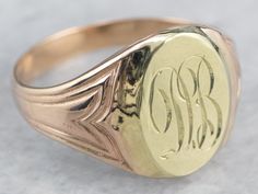 "Featuring components from different eras, this one-of-a-kind signet ring is a delightful combination of green and rose gold! The monogram at the center is beautifully engraved in ornate French script, while the ring's shoulders have subtle motifs that catch the light and shine. Please note that this signet ring has an original monogram, and unfortunately, this piece cannot be altered without affecting the quality of the piece. Please feel free to contact us to help you find your perfect signet Luxury Engraved Signet Ring Collectible, Vintage Oval Signet Ring With Hallmarks, Collectible Yellow Gold Signet Ring With Engraving Option, Antique Oval Initial Ring For Formal Occasions, Antique Oval Signet Ring Stamped 14k, Victorian Oval Signet Ring With Maker's Mark, Victorian Oval Rings With Engraving Option, Antique Oval 14k Stamped Signet Ring, Victorian Oval Ring With Engraving Option