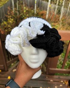 a person is holding up a crocheted white and black hat