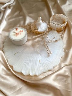 an assortment of jewelry sits on a white plate with a gold satin covering behind it