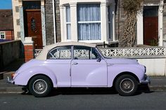 an old purple car parked in front of a house