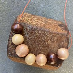 a wooden bead necklace hanging on a piece of wood with string attached to it