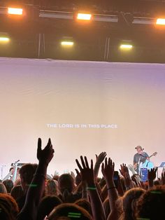 a large group of people at a concert with their hands up in front of them