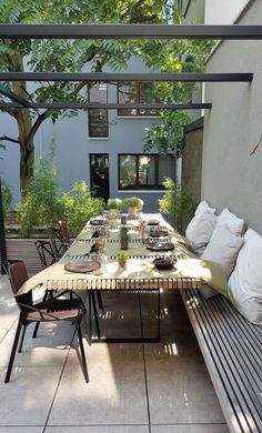 an outdoor dining area with benches and table set for six on tiled floored patio