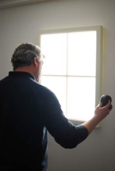 a man holding a hair dryer in front of a window