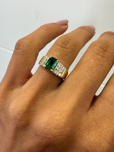 a woman's hand with an emerald and diamond ring