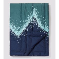 a blue and green blanket with white dots on it's side, sitting on a grey surface