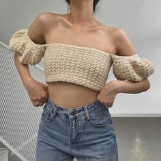 a woman in high waisted jeans and off the shoulder cropped sweater poses for a photo